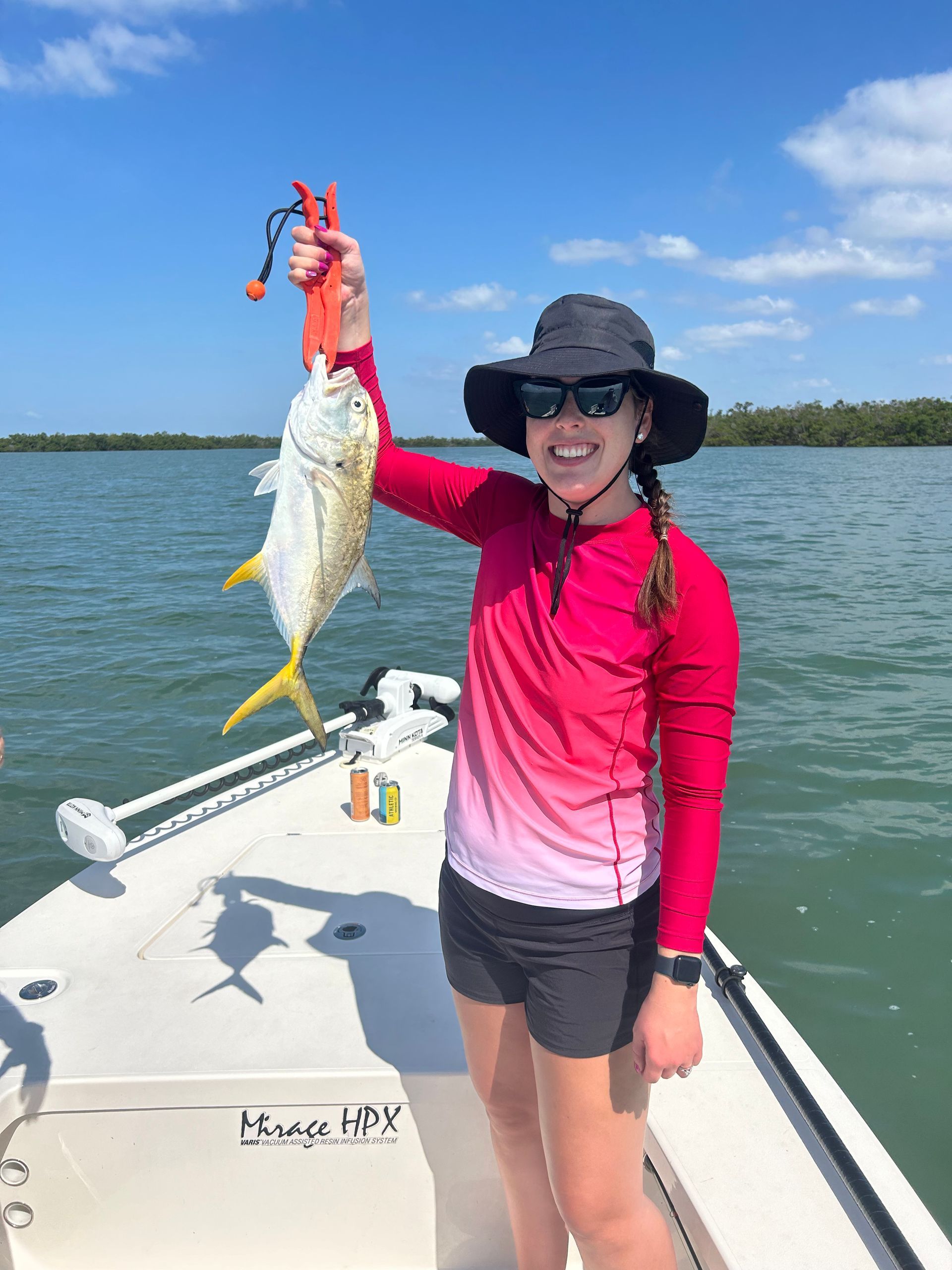 A woman is standing on a boat holding a fish.