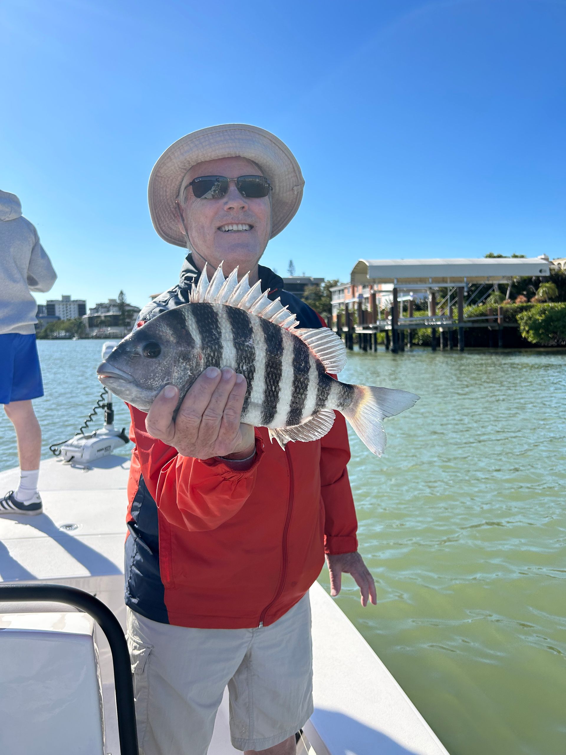 A man is holding a fish on a boat in the water.