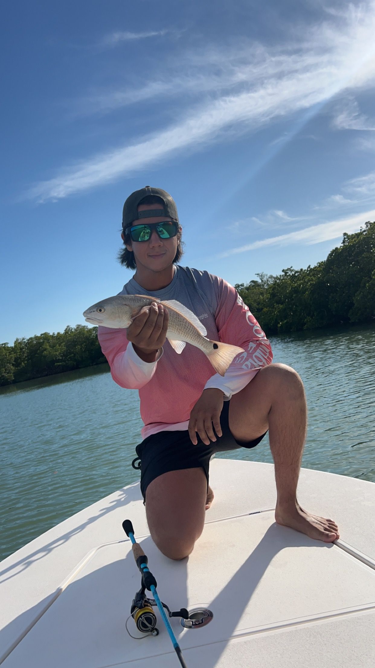 A man is kneeling on a boat holding a fish.