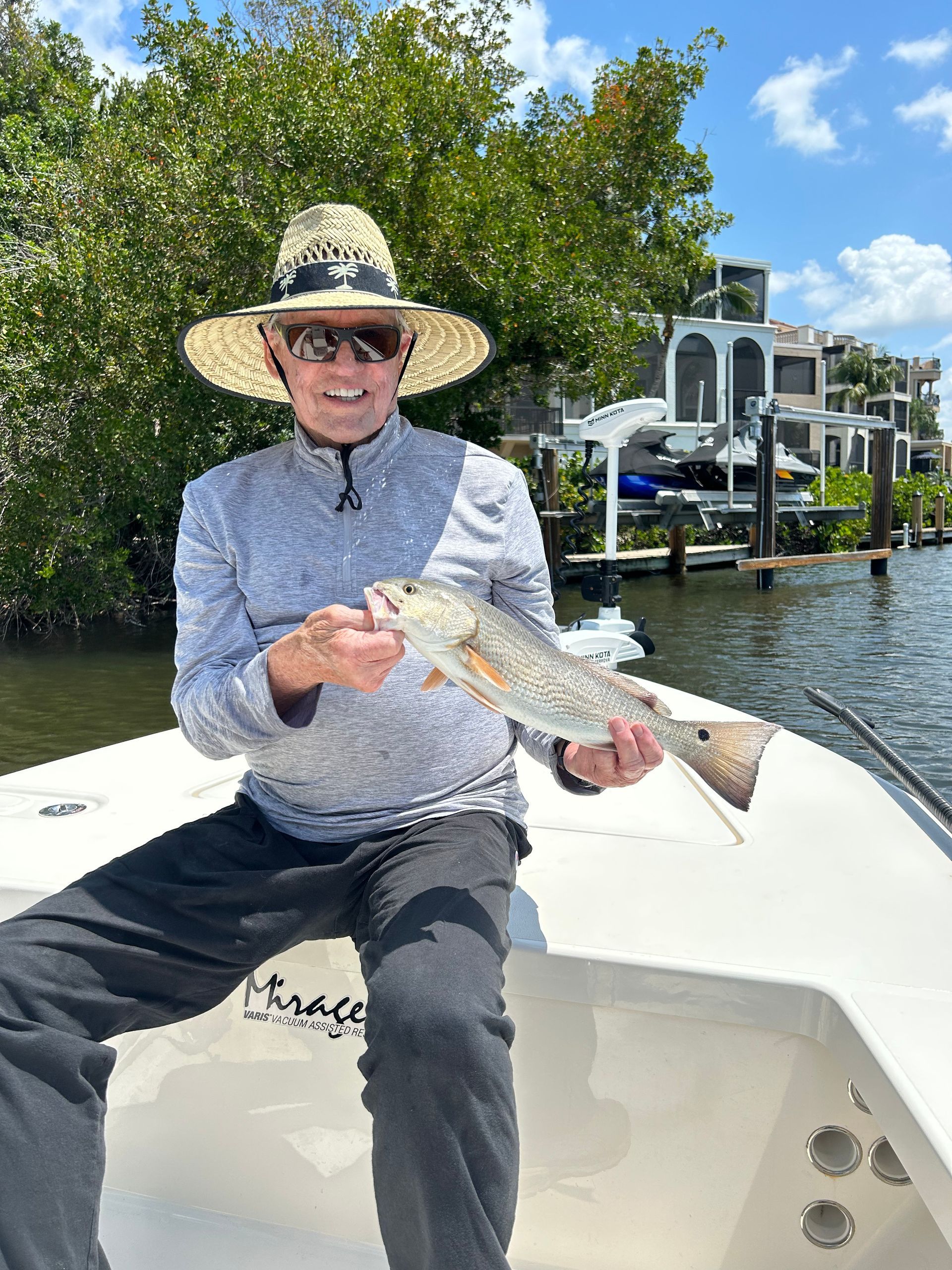 A man is sitting on a boat holding a fish.