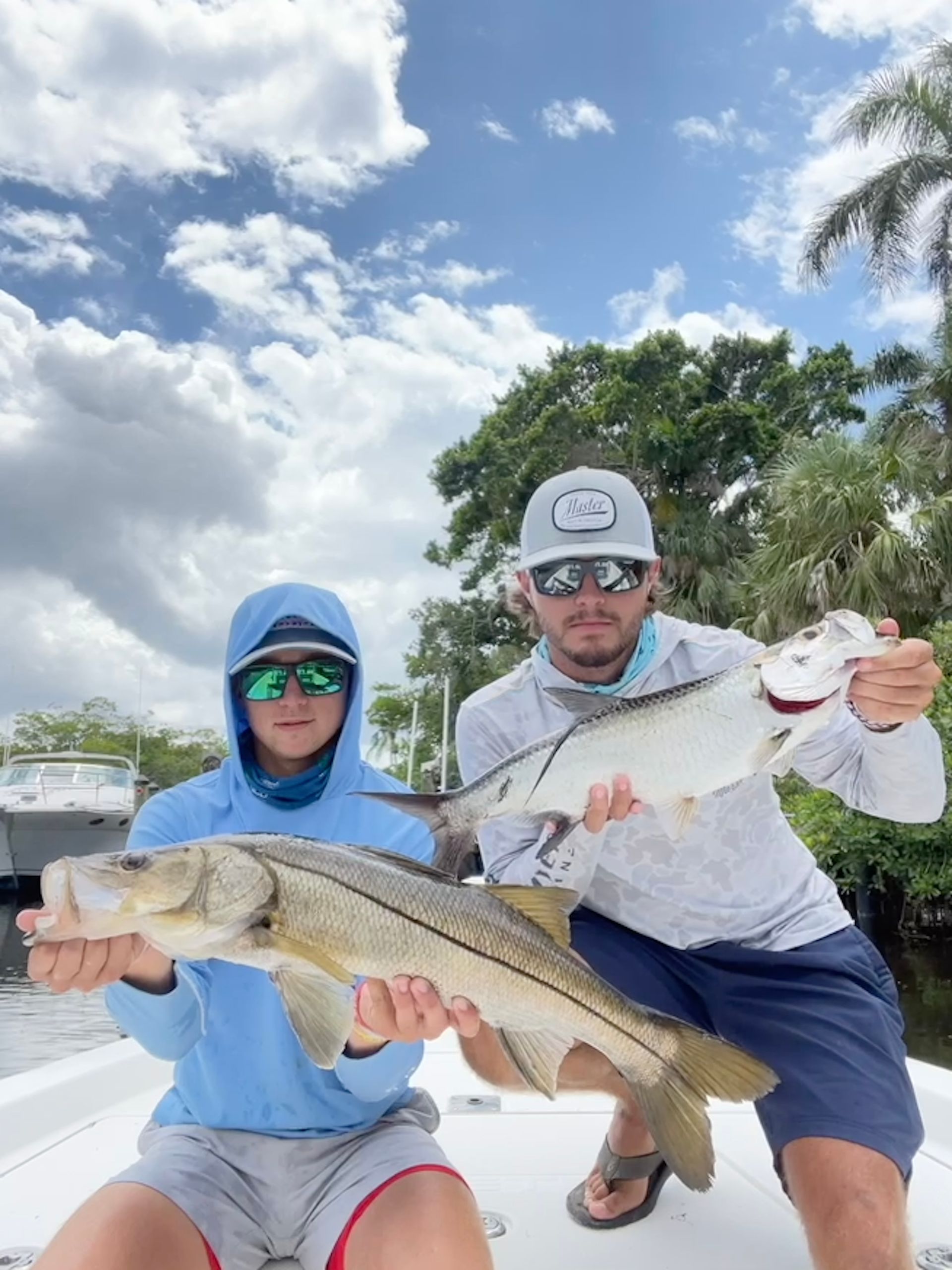 Two men are holding two fish on a boat.
