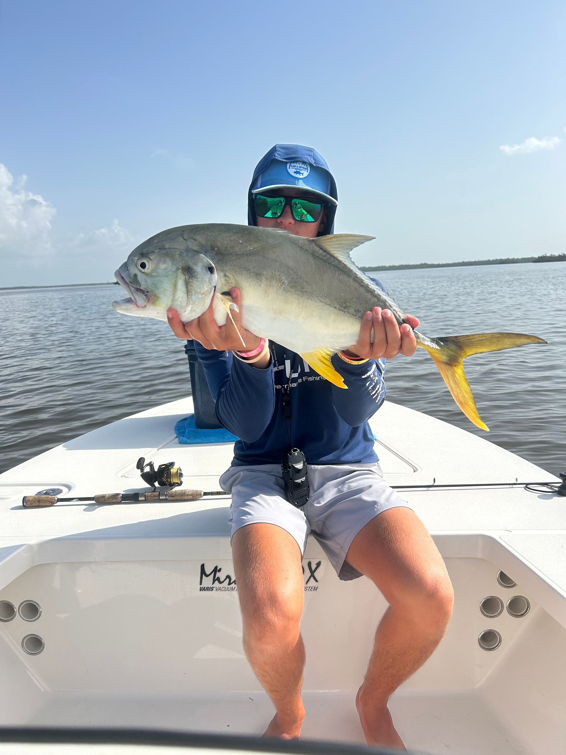 A man is sitting on a boat holding a fish.