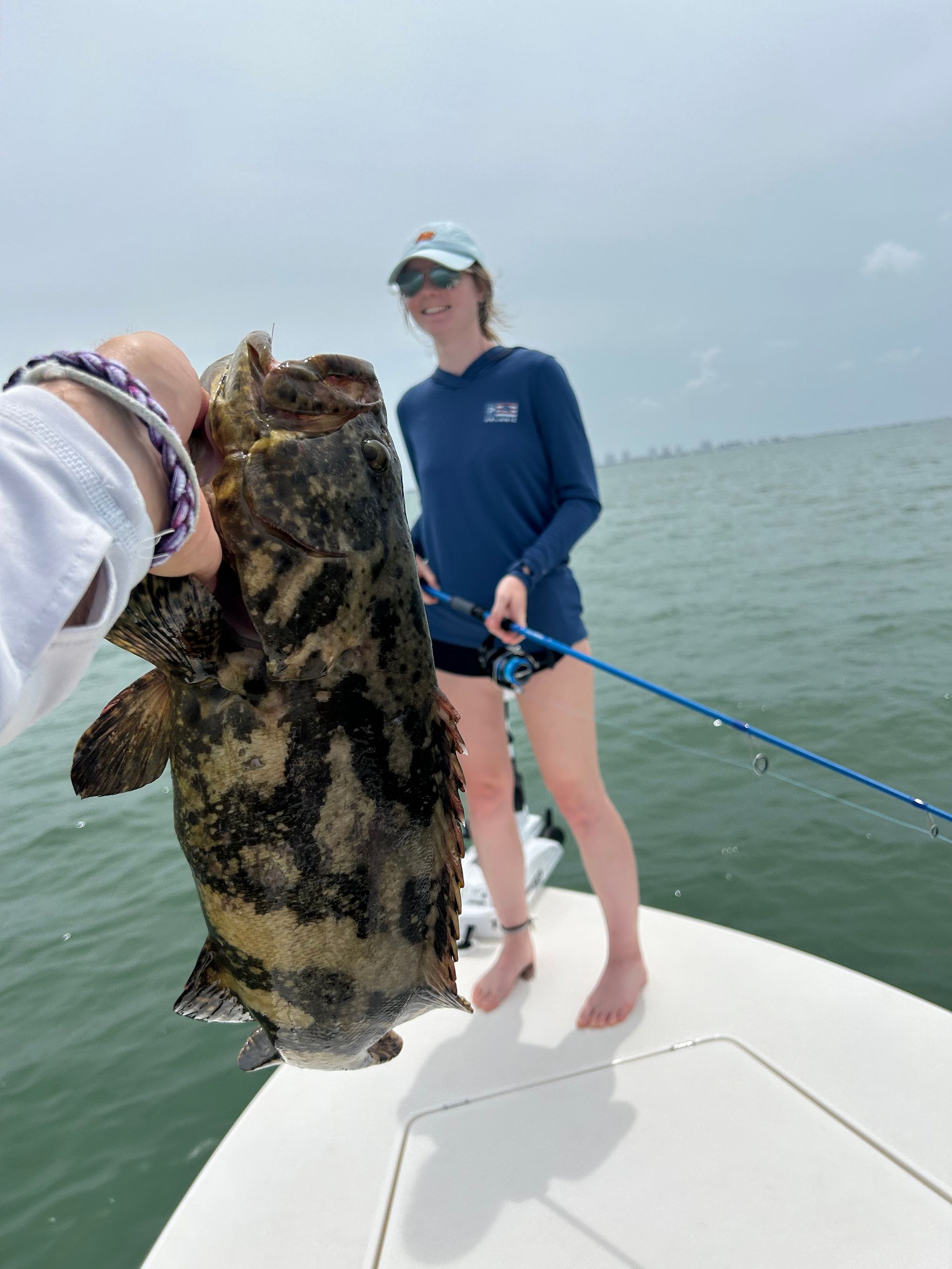 A woman is holding a large fish on a boat