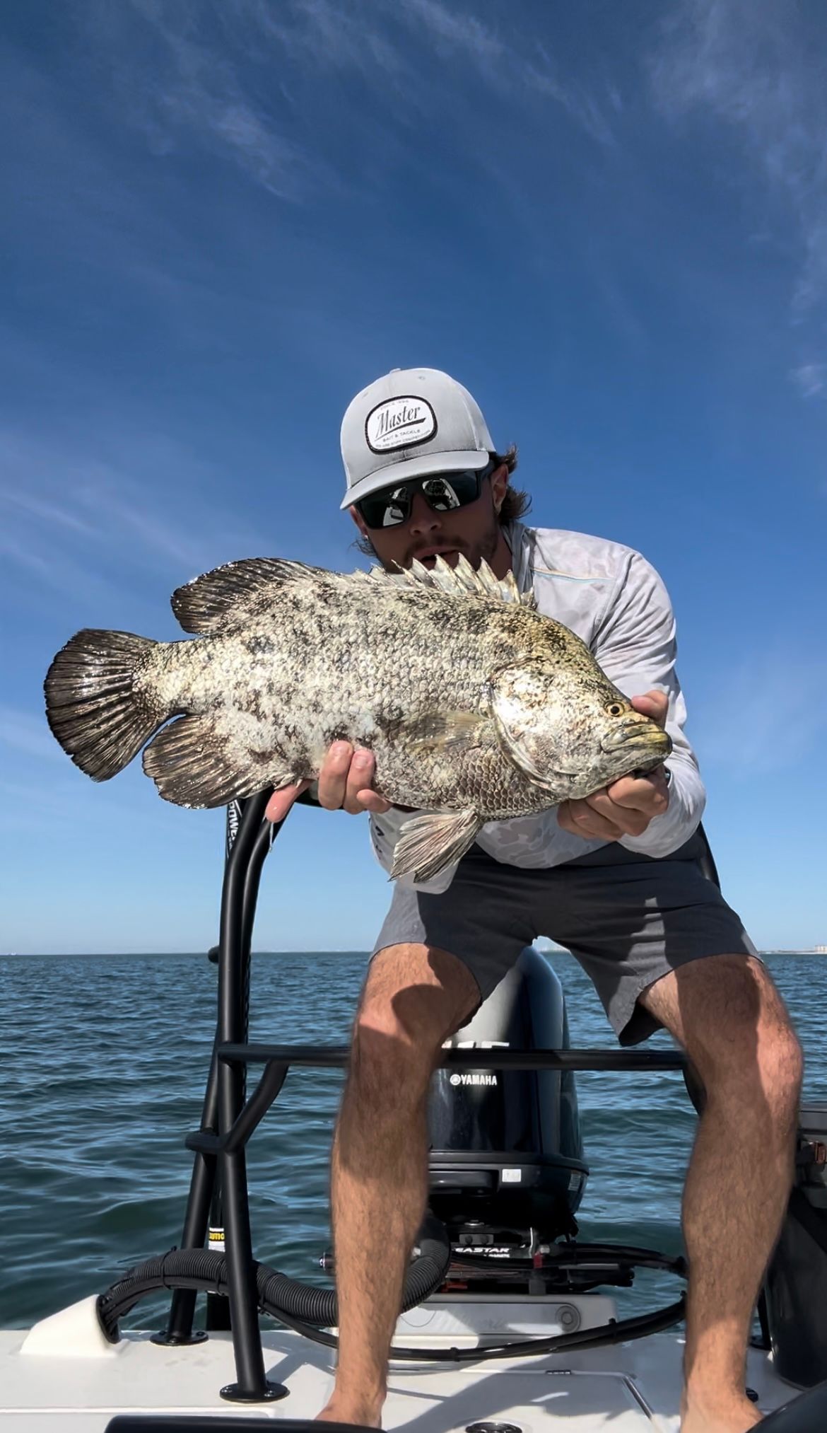 A man is holding a large fish on a boat.