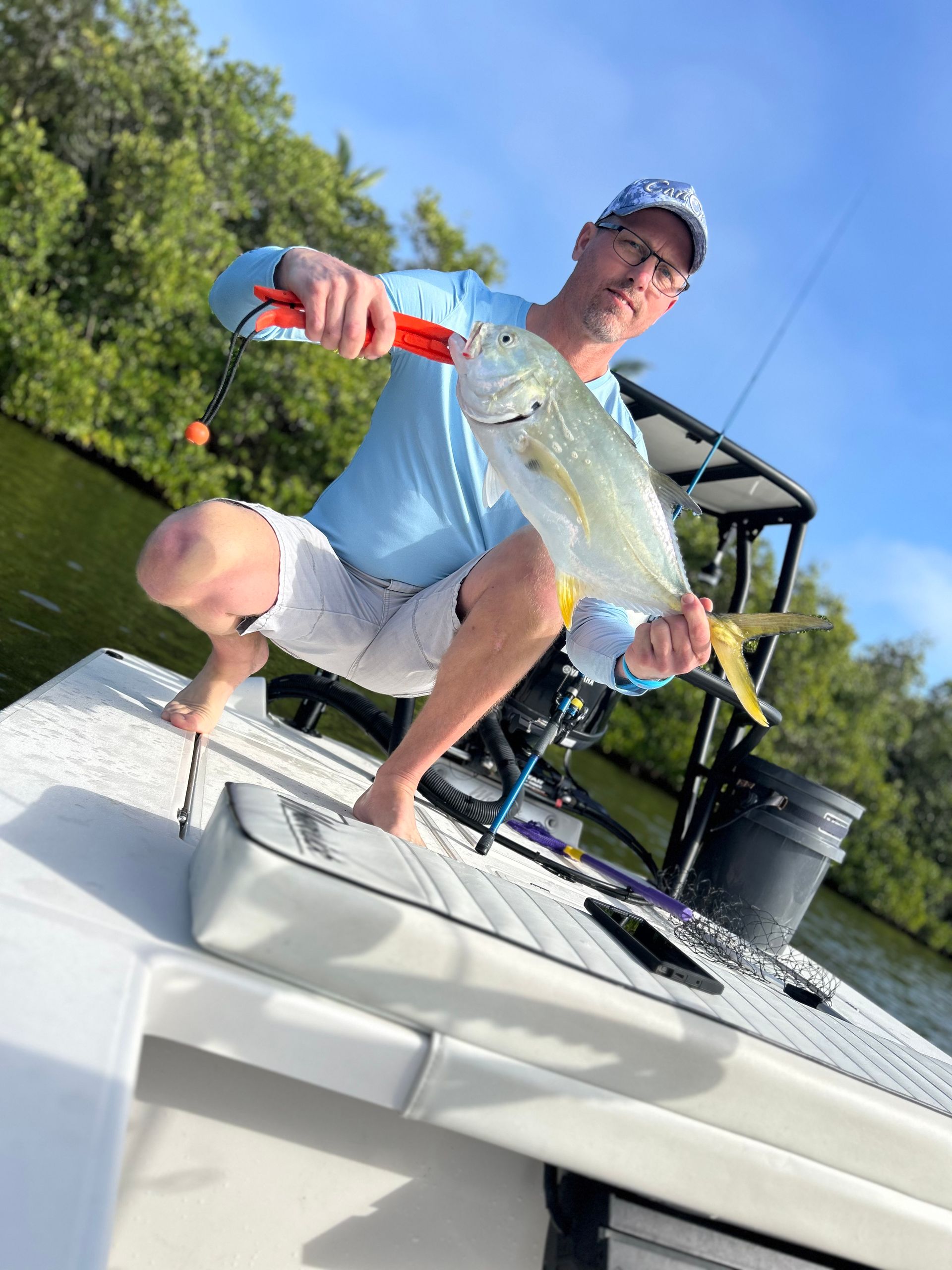A man is kneeling on a boat holding a fish.