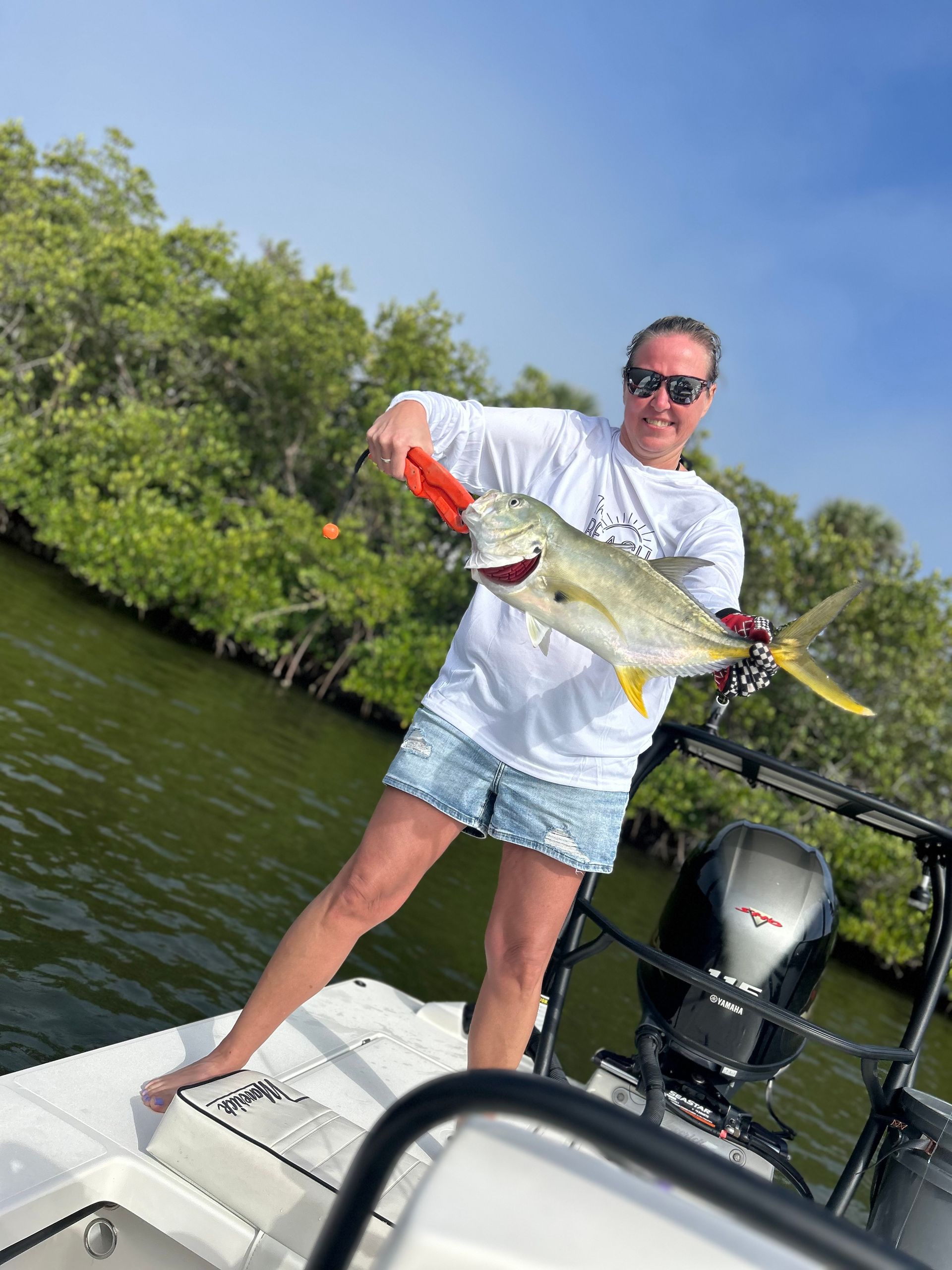 A woman is standing on a boat holding a fish.