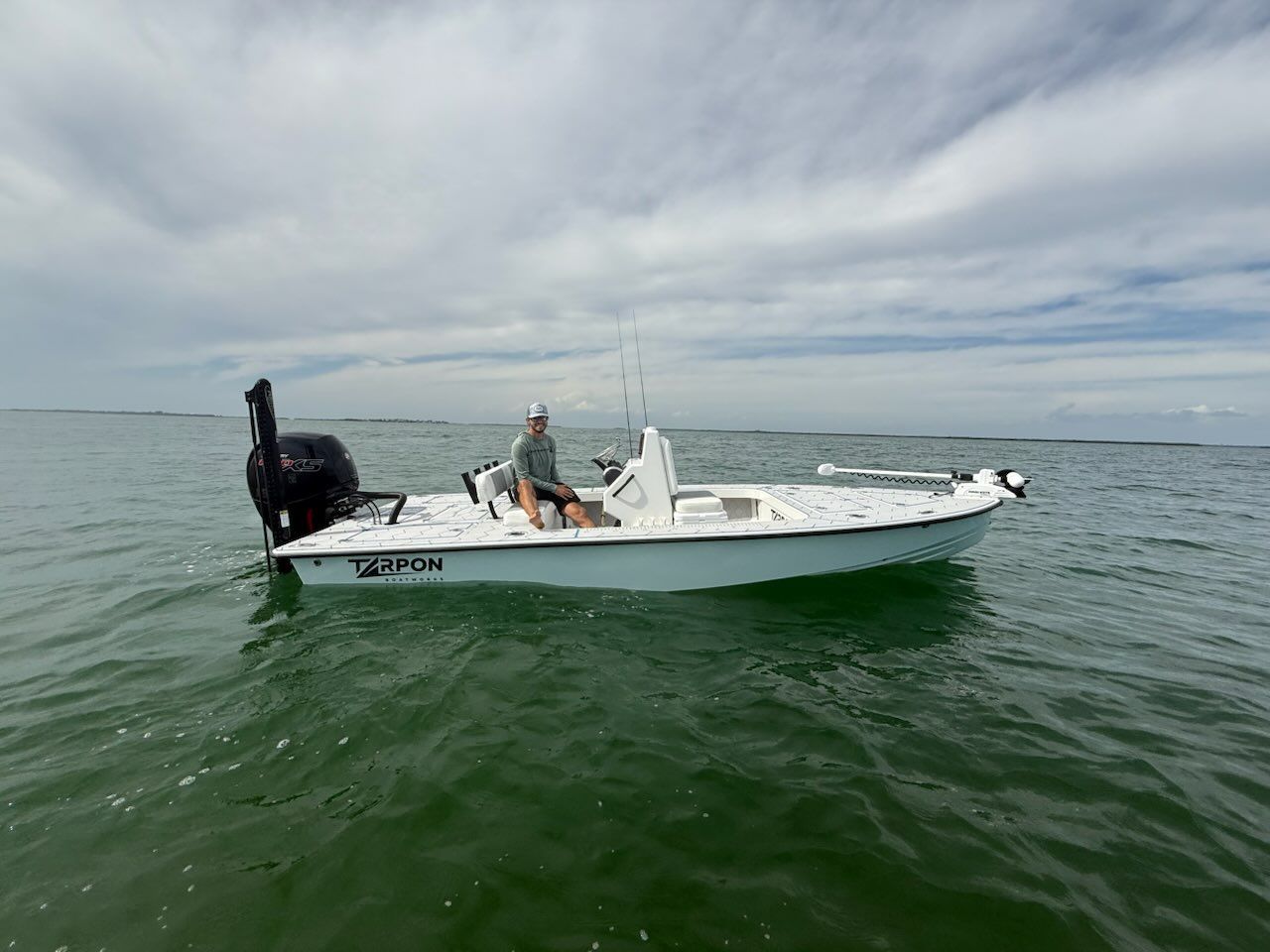 A man is sitting on a boat in the ocean.