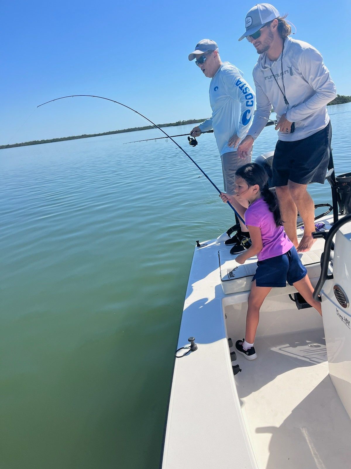 A group of people are fishing on a boat in the water.