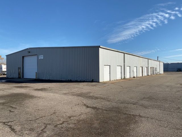 A large metal building with a white door and a blue sky in the background.