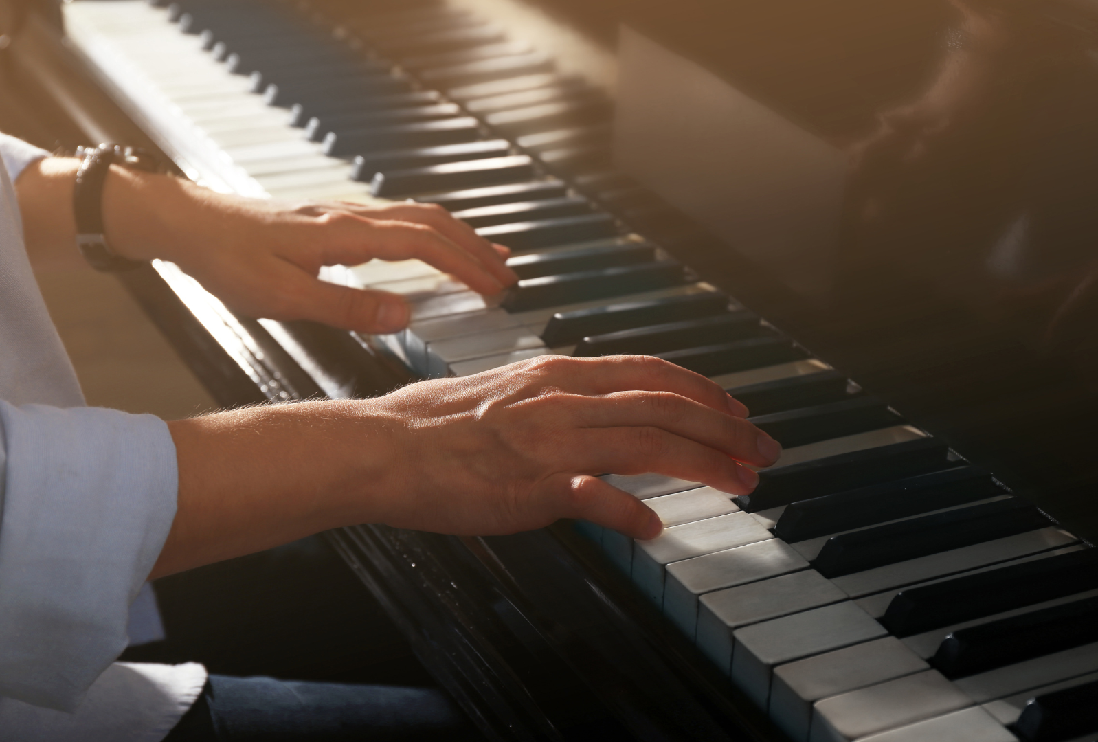 A person is playing a piano with their hands on the keys