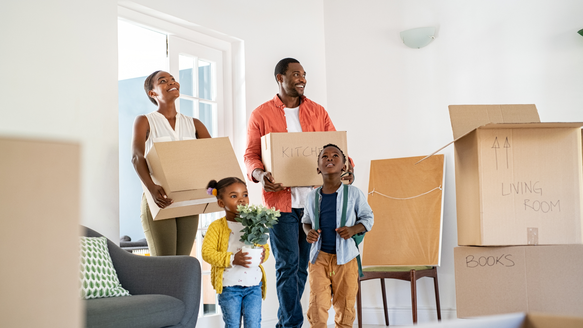 A family is moving into a new home and carrying boxes.