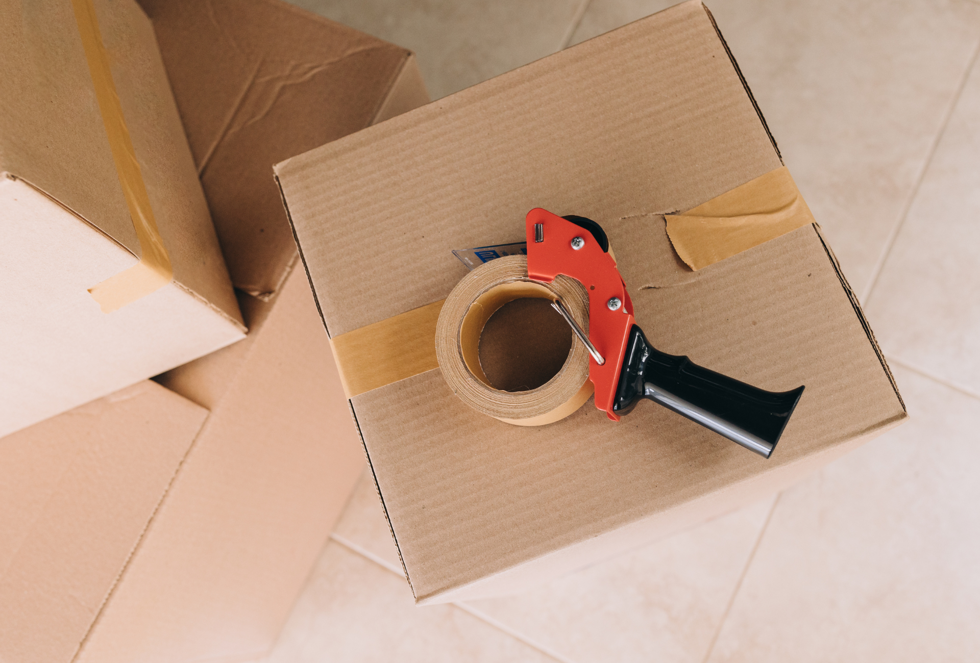 A cardboard box with a tape dispenser on top of it.