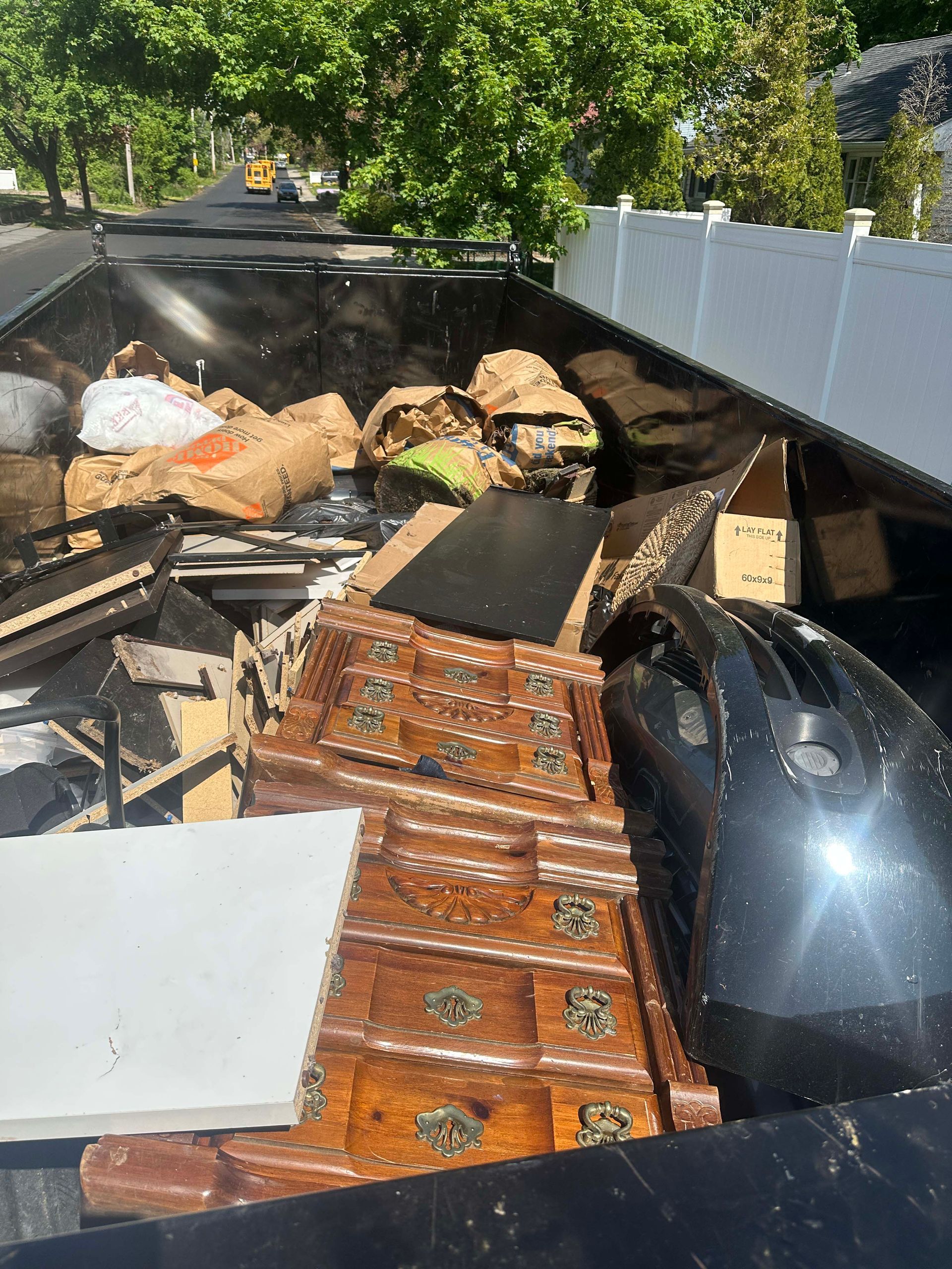 A truck filled with lots of junk is parked on the side of the road.