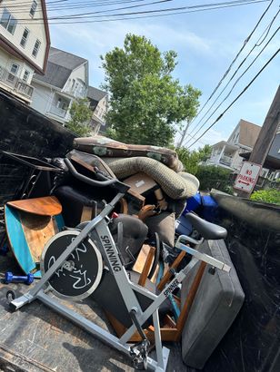 A spinning bike is sitting on top of a pile of junk.