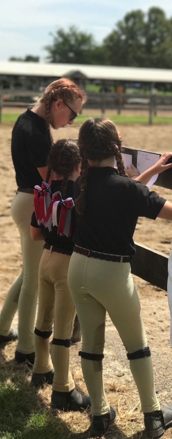 A young girl wearing a helmet is riding a brown horse