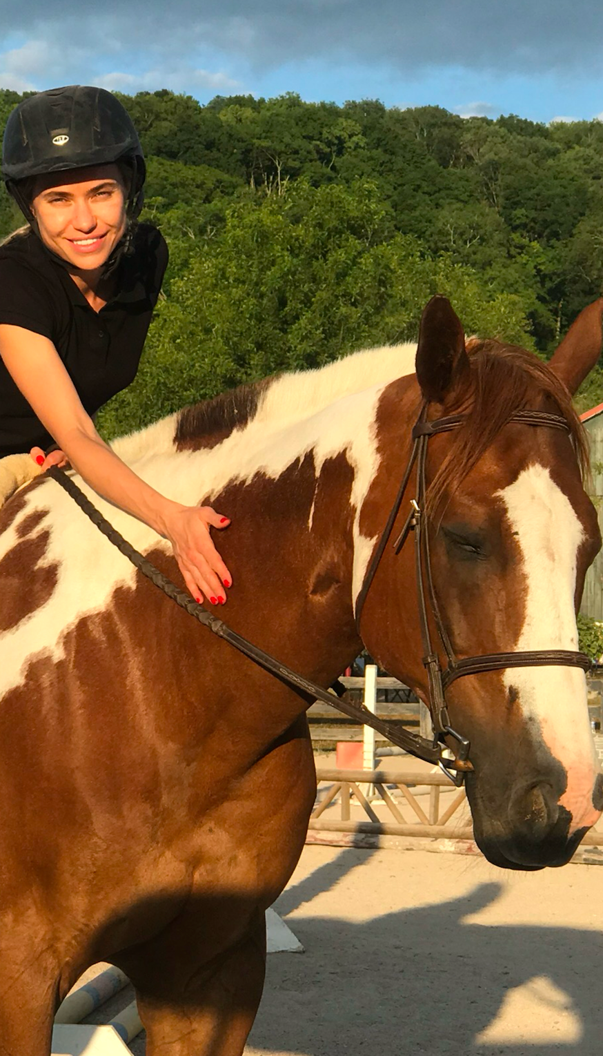 A woman is riding on the back of a brown and white horse.