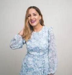 Therapist's hand holding pen, patient in background seated on a couch, focused.