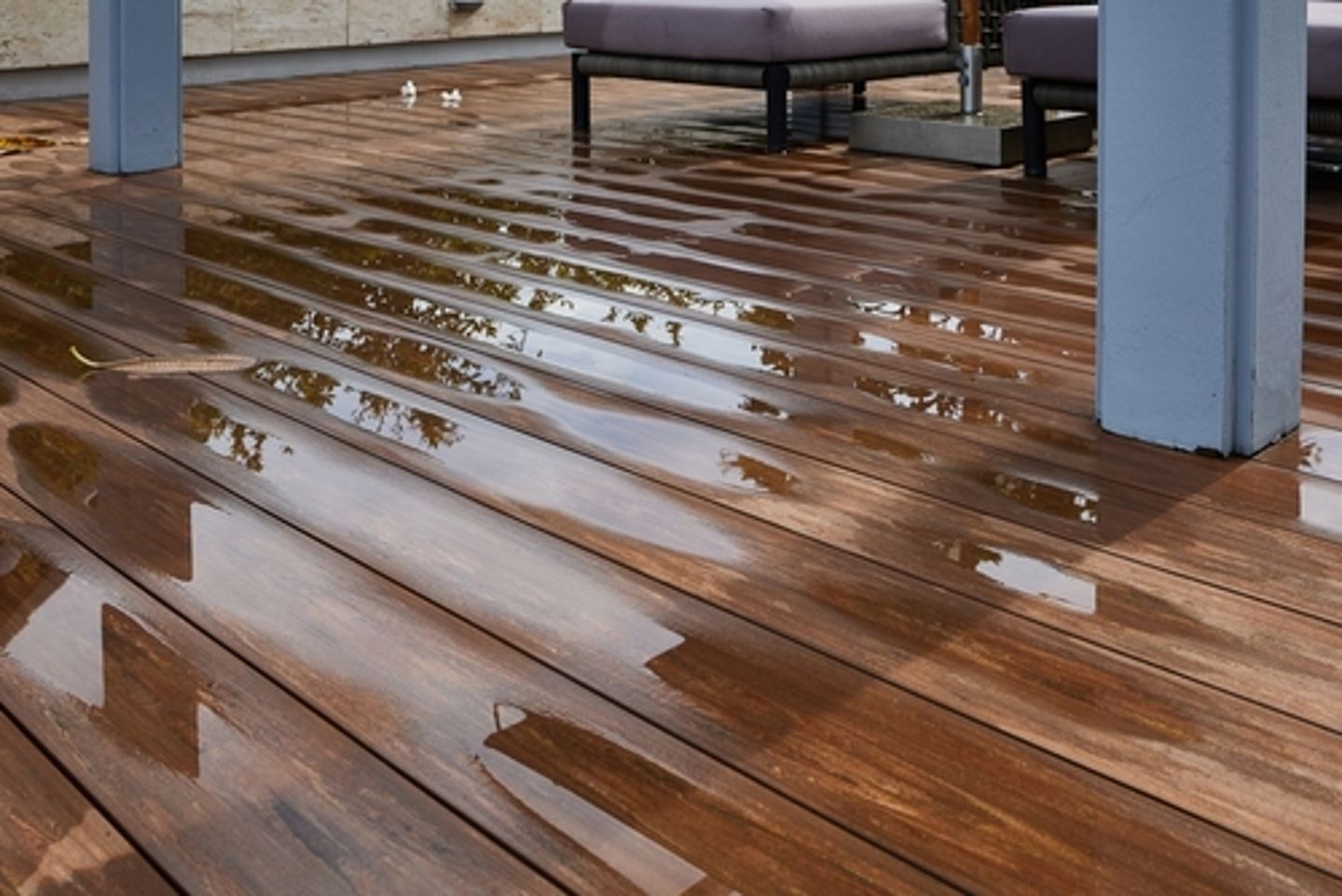 Water pooled on wooden floor from pipe leak.