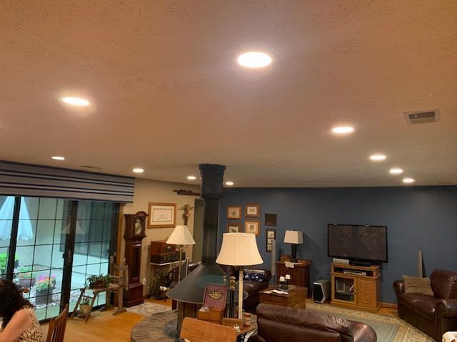 Living room with recessed lights, blue wall, TV, leather furniture, and a grandfather clock.