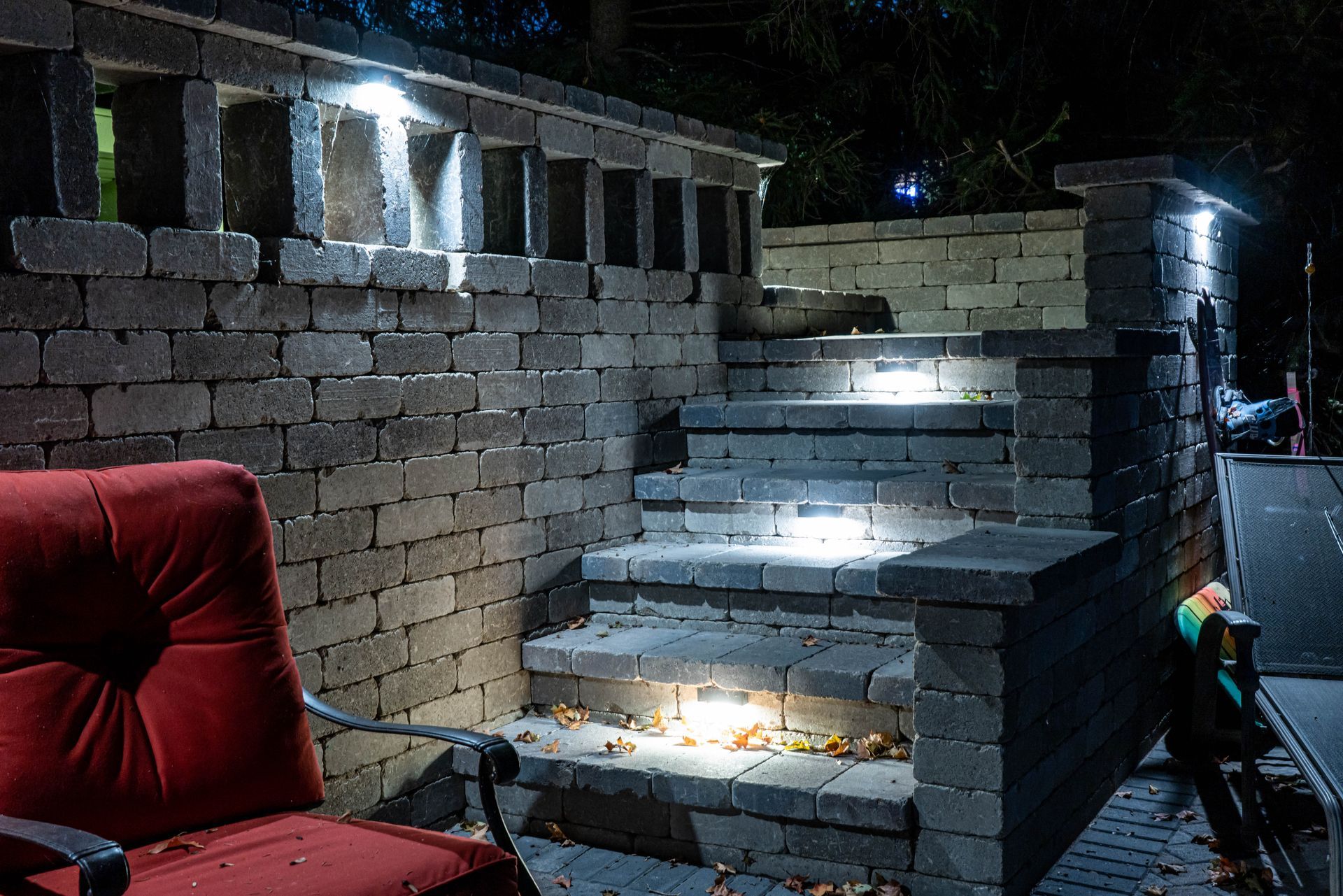 Brick staircase with built-in lights, red armchair, night setting.