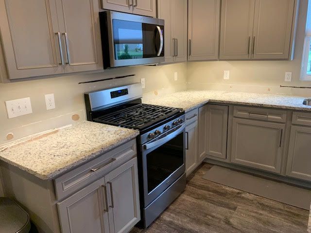 Kitchen with gray cabinets, granite countertops, stainless steel appliances, and under-cabinet lighting.
