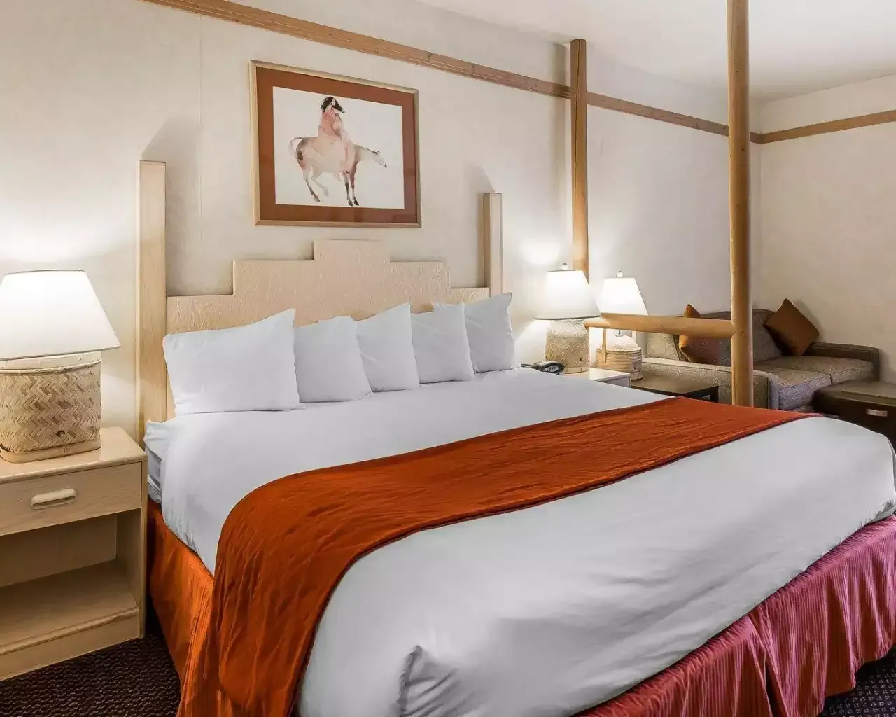 A hotel room with a king size bed and a picture on the wall above it.