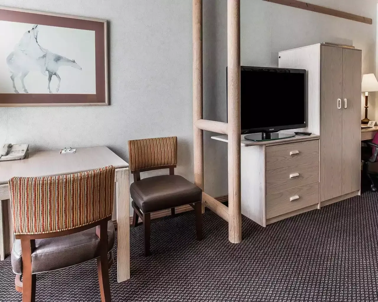 A hotel room with a desk , chair and television