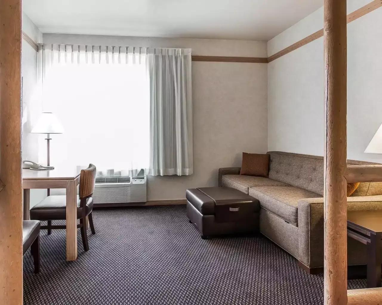 A hotel room with a couch , table and chairs