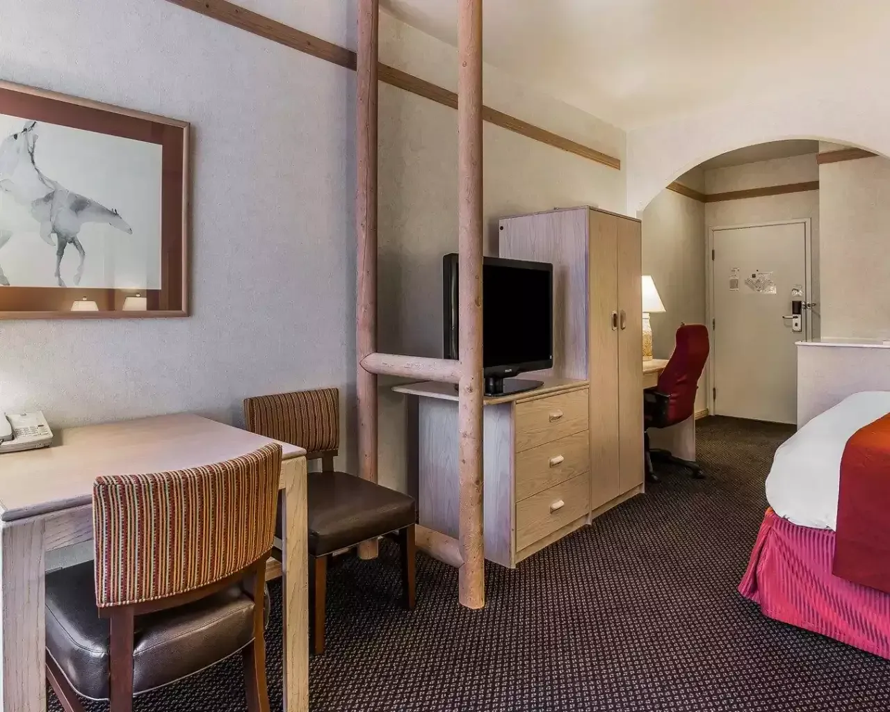 A hotel room with a bed , desk , chairs and television