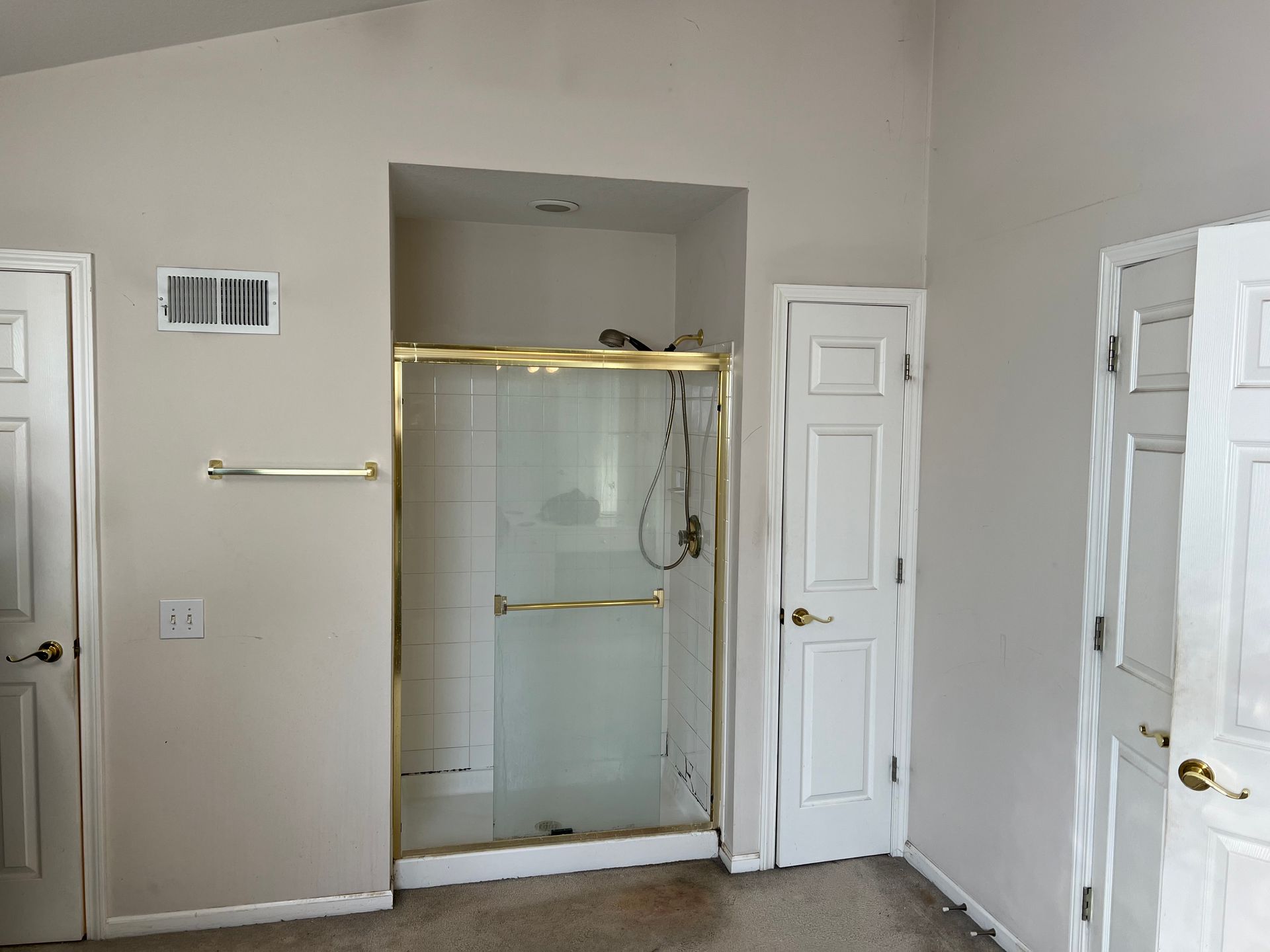 Bathroom with a shower, two doors, a towel rack, and an air vent.