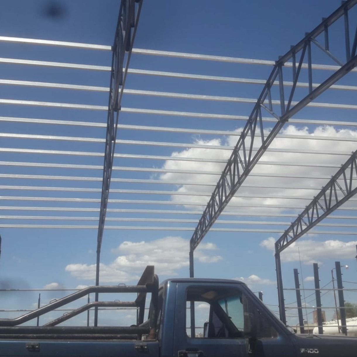 Camión azul con techo de acero contra un cielo azul con nubes.