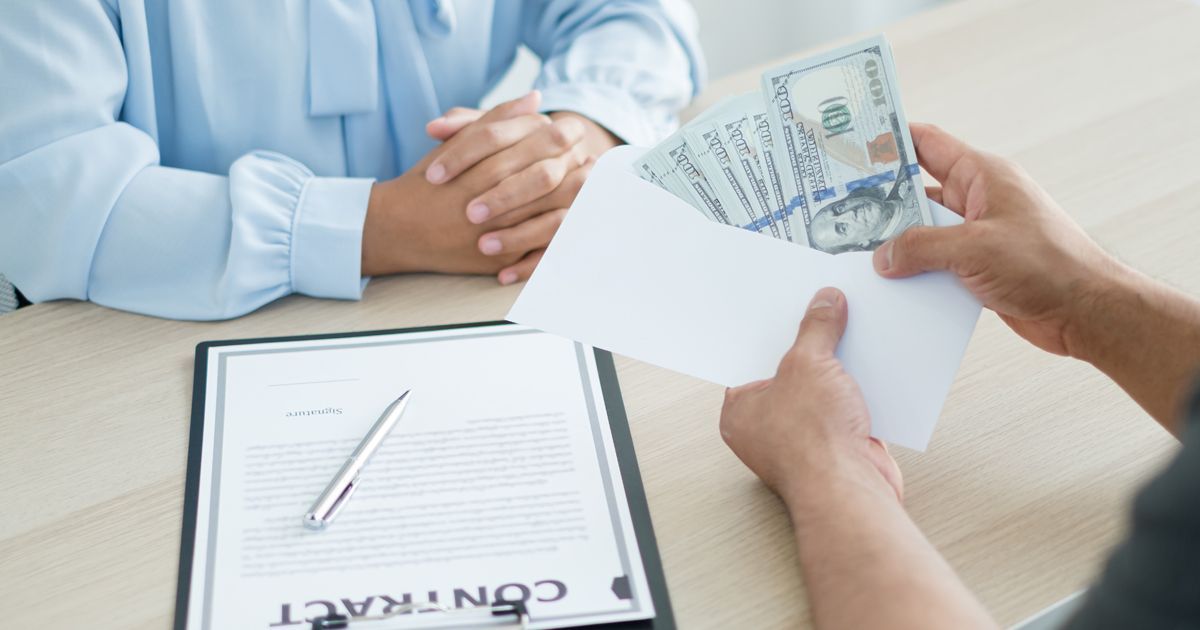 A man is putting money in an envelope to a woman.