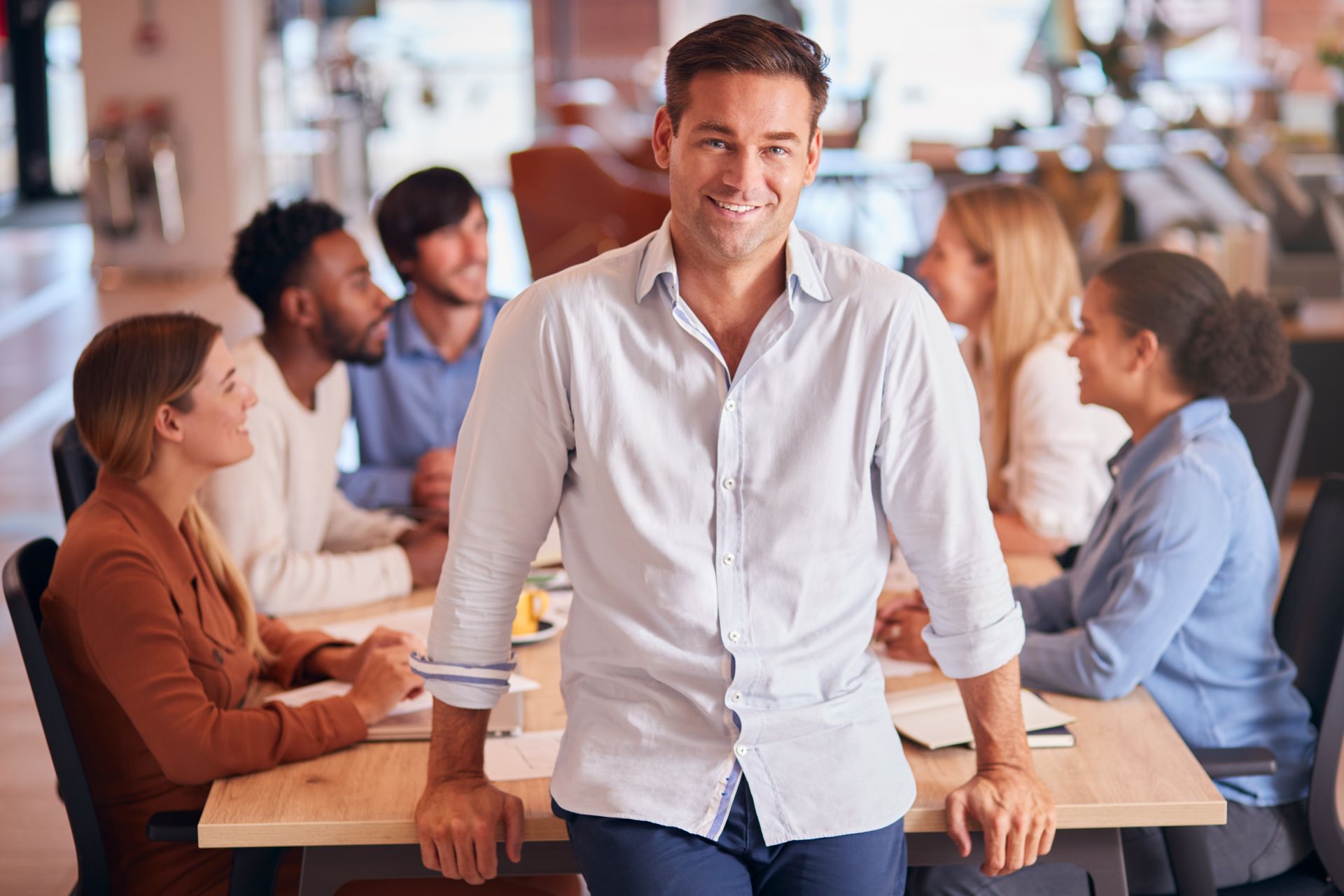 A man is sitting at a table in front of a group of people.