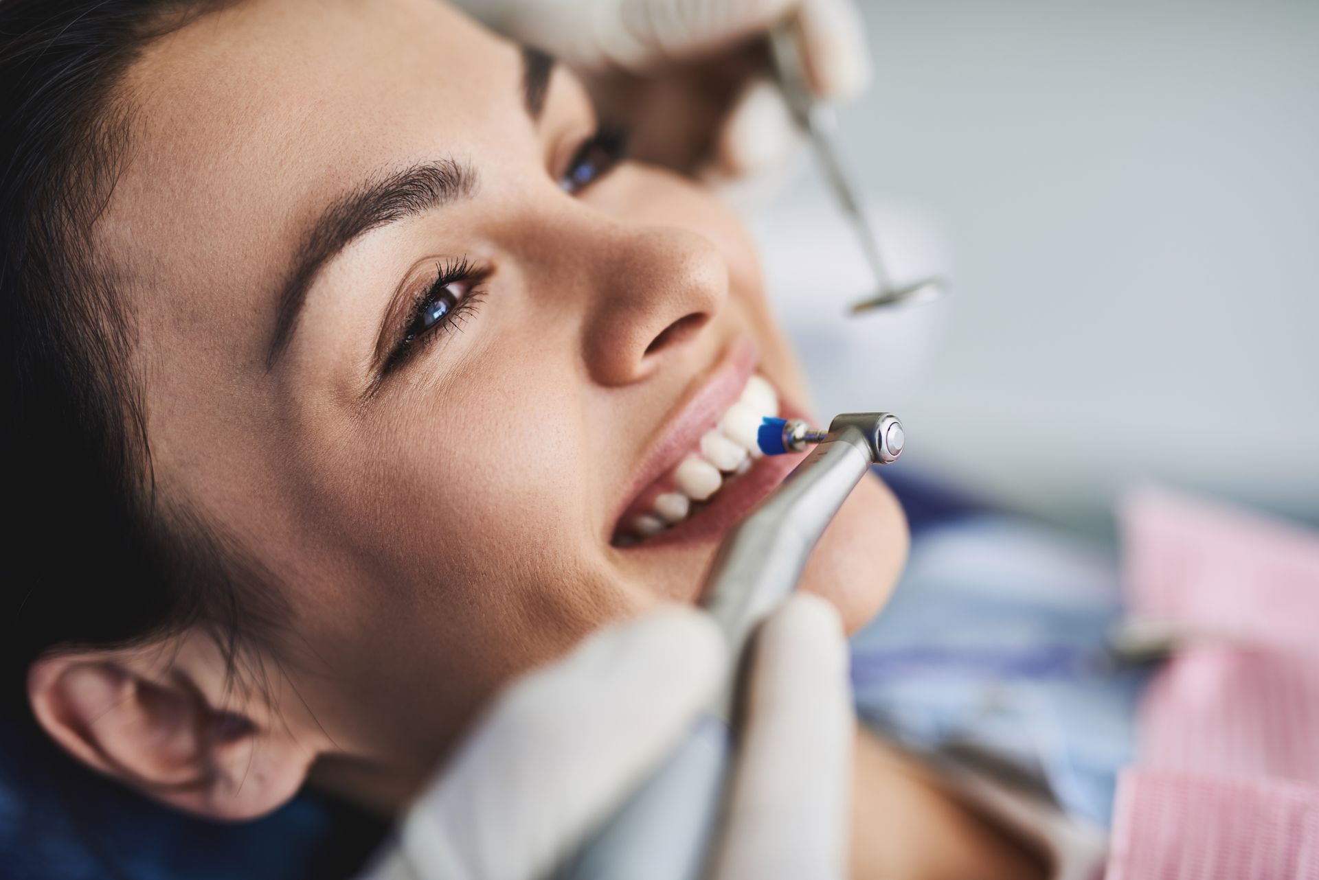Dentist using a drill on a smiling patient in a dental chair