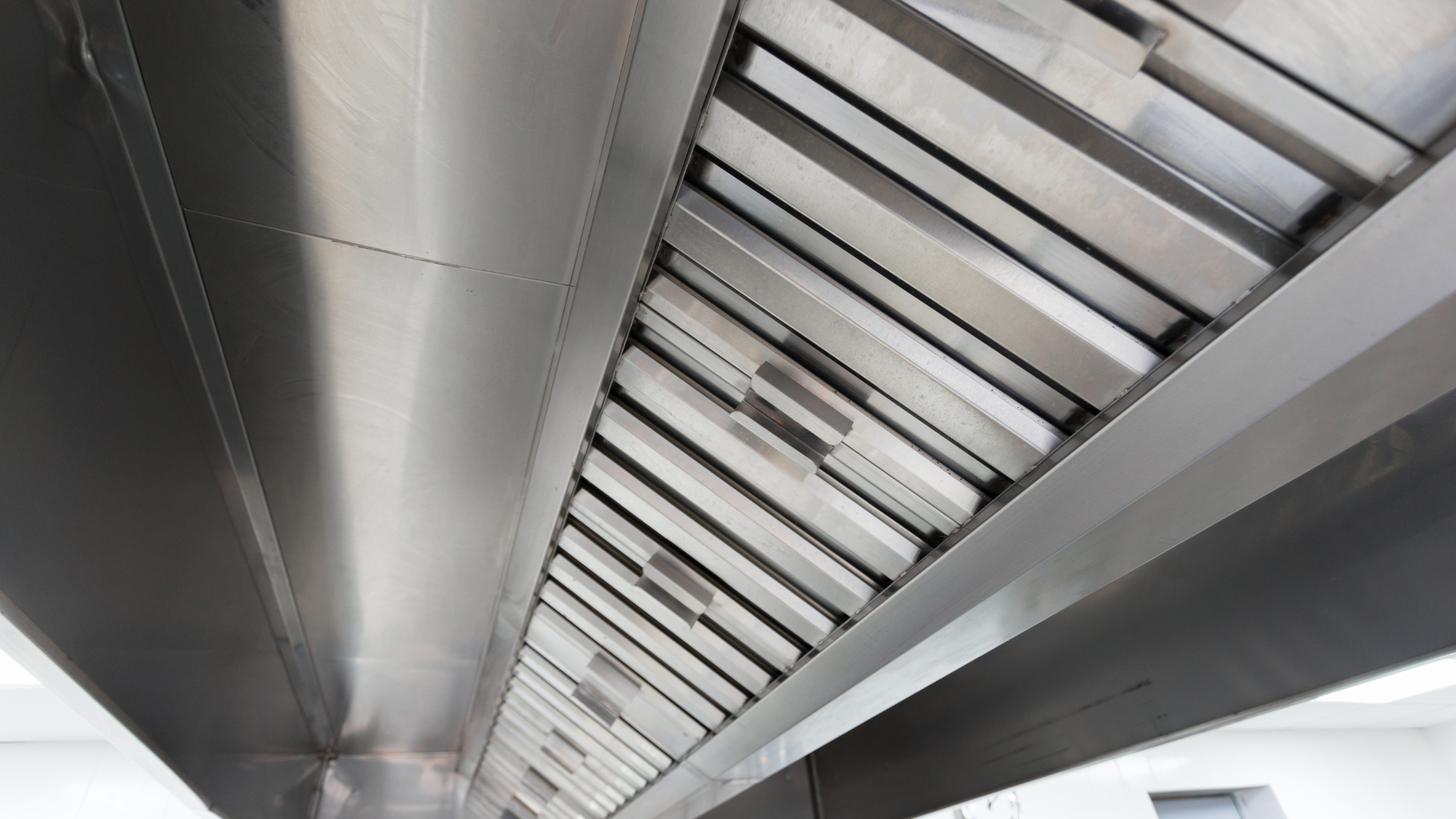 A close up of a stainless steel exhaust hood in a kitchen.