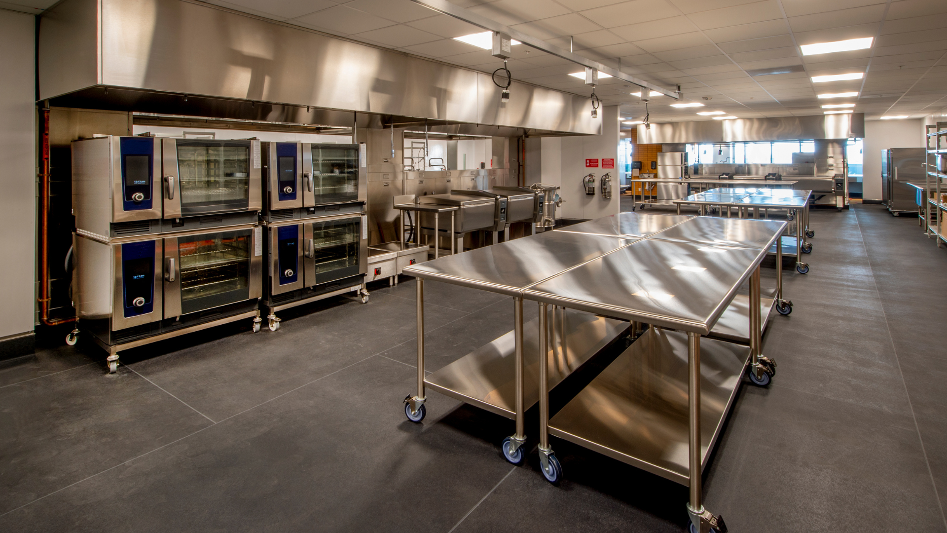 A large kitchen with stainless steel tables and ovens.
