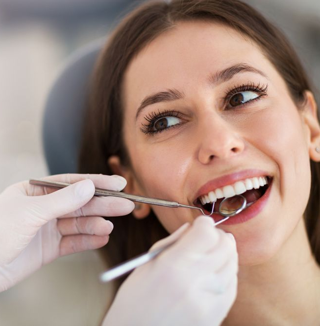 Woman at dentist smiling while teeth are being examined.