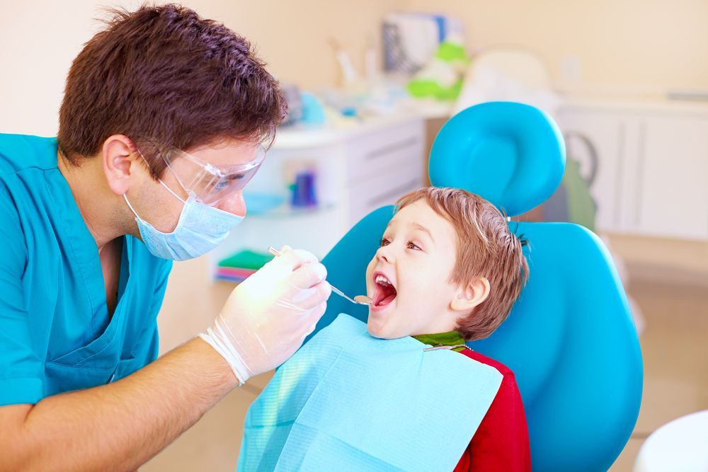 A young boy is getting his teeth examined by a dentist.