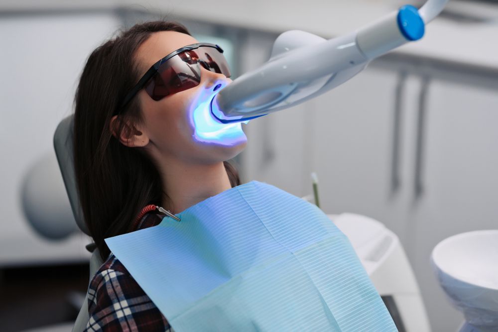 A woman is holding a whitening device in her hand.