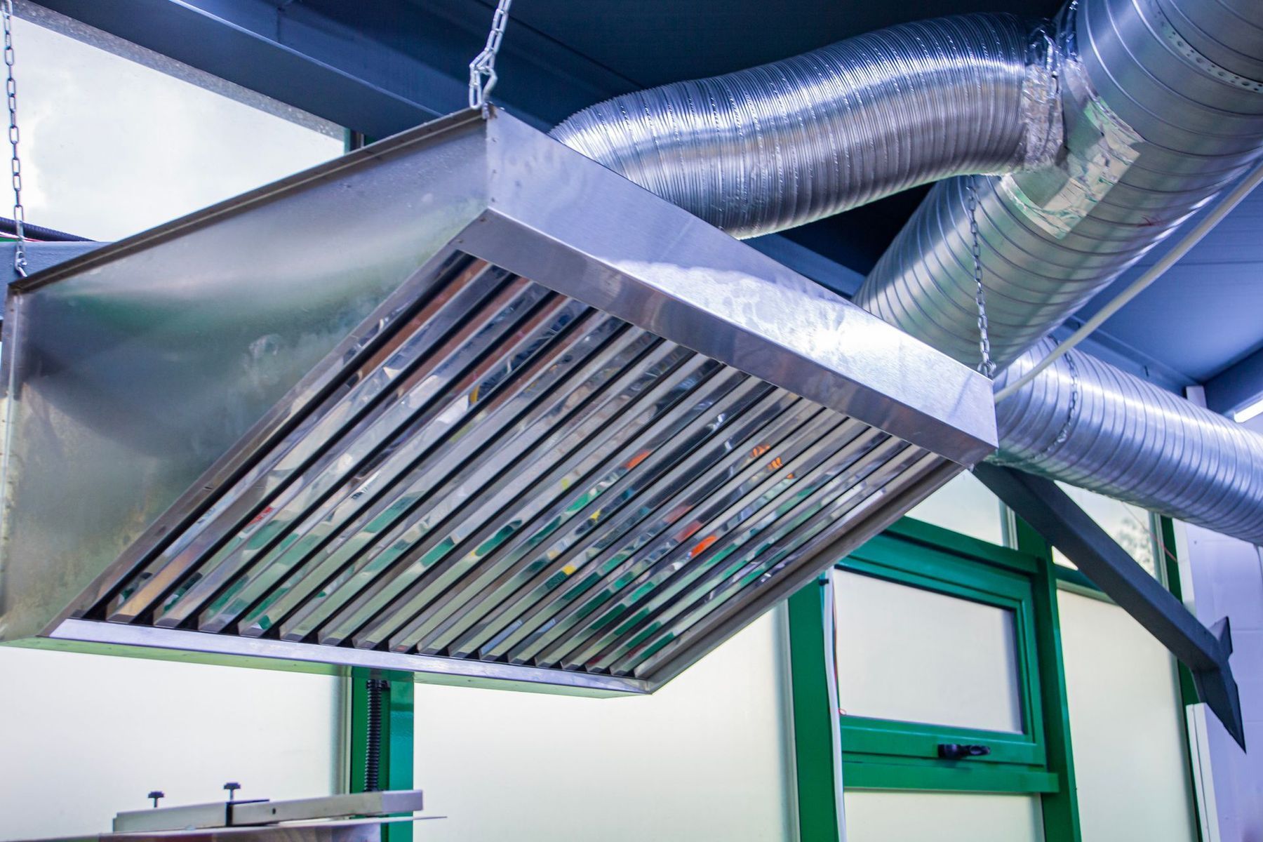 Stainless steel commercial kitchen vent hood with ductwork.