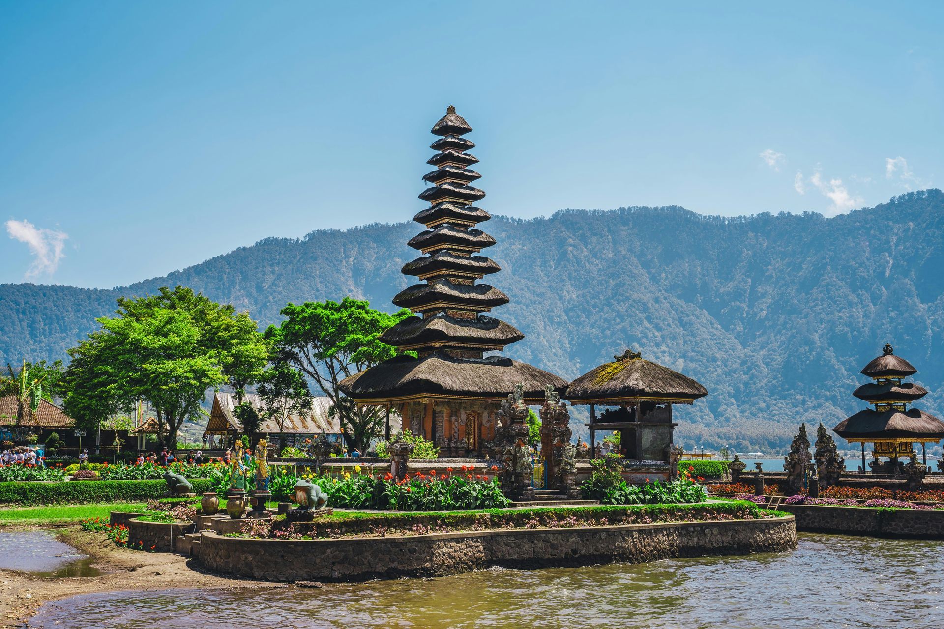 Balinese temple on a small island with a multi-tiered pagoda, surrounded by water and mountains