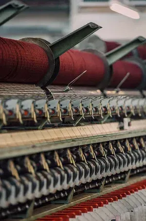 Close-up of a textile machine spinning red yarn spools in a factory