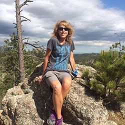 A woman is sitting on a rock on top of a mountain.
