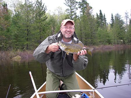 A man in a canoe is holding a fish in his hands.