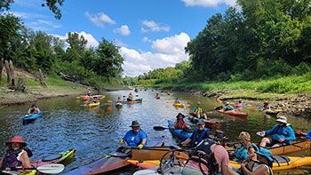 A group of people are riding kayaks down a river.
