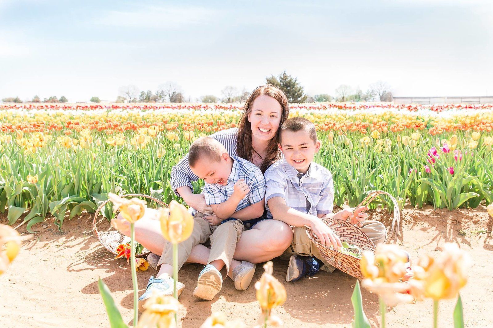 A woman and two children are sitting in a field of flowers.