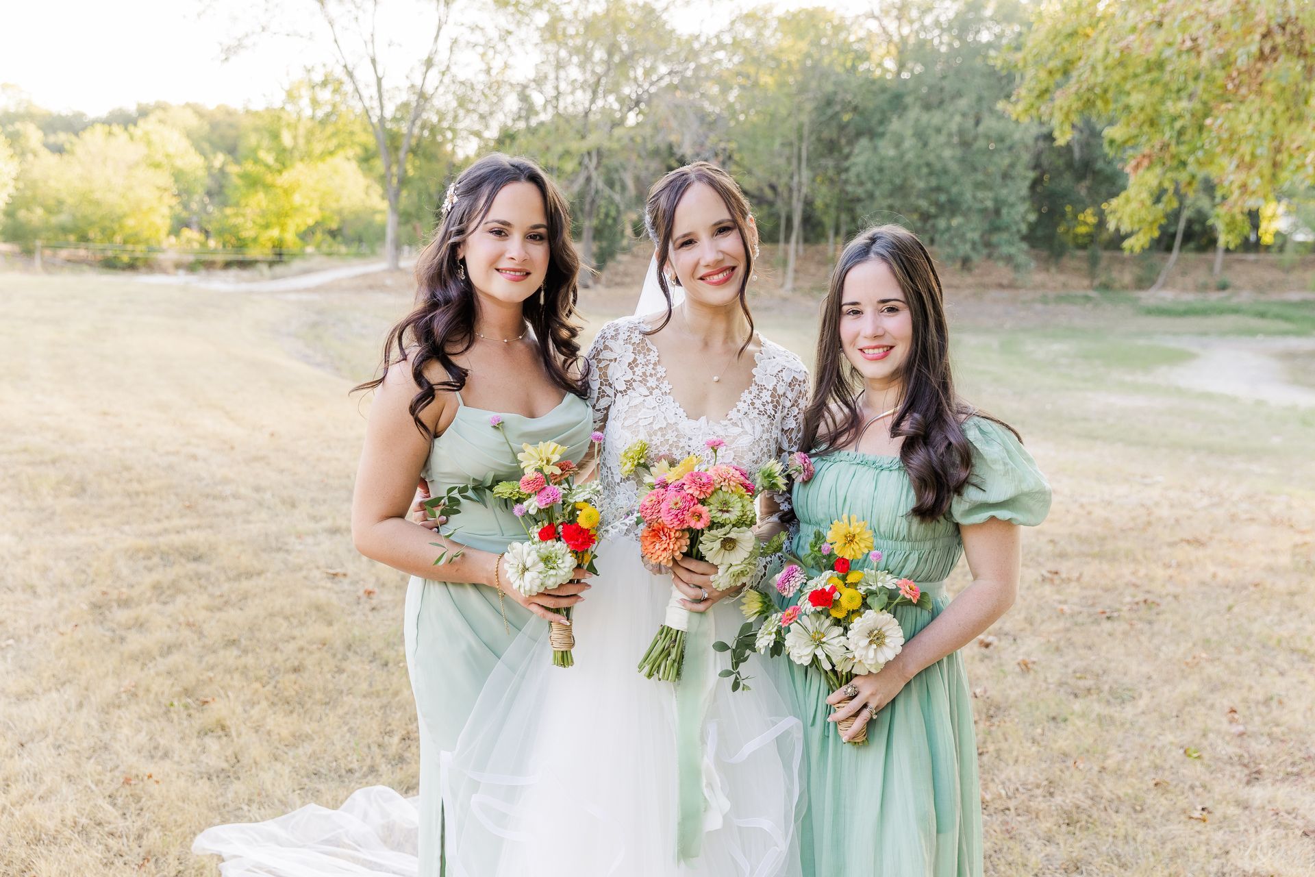 A bride and her bridesmaids are posing for a picture in a field.