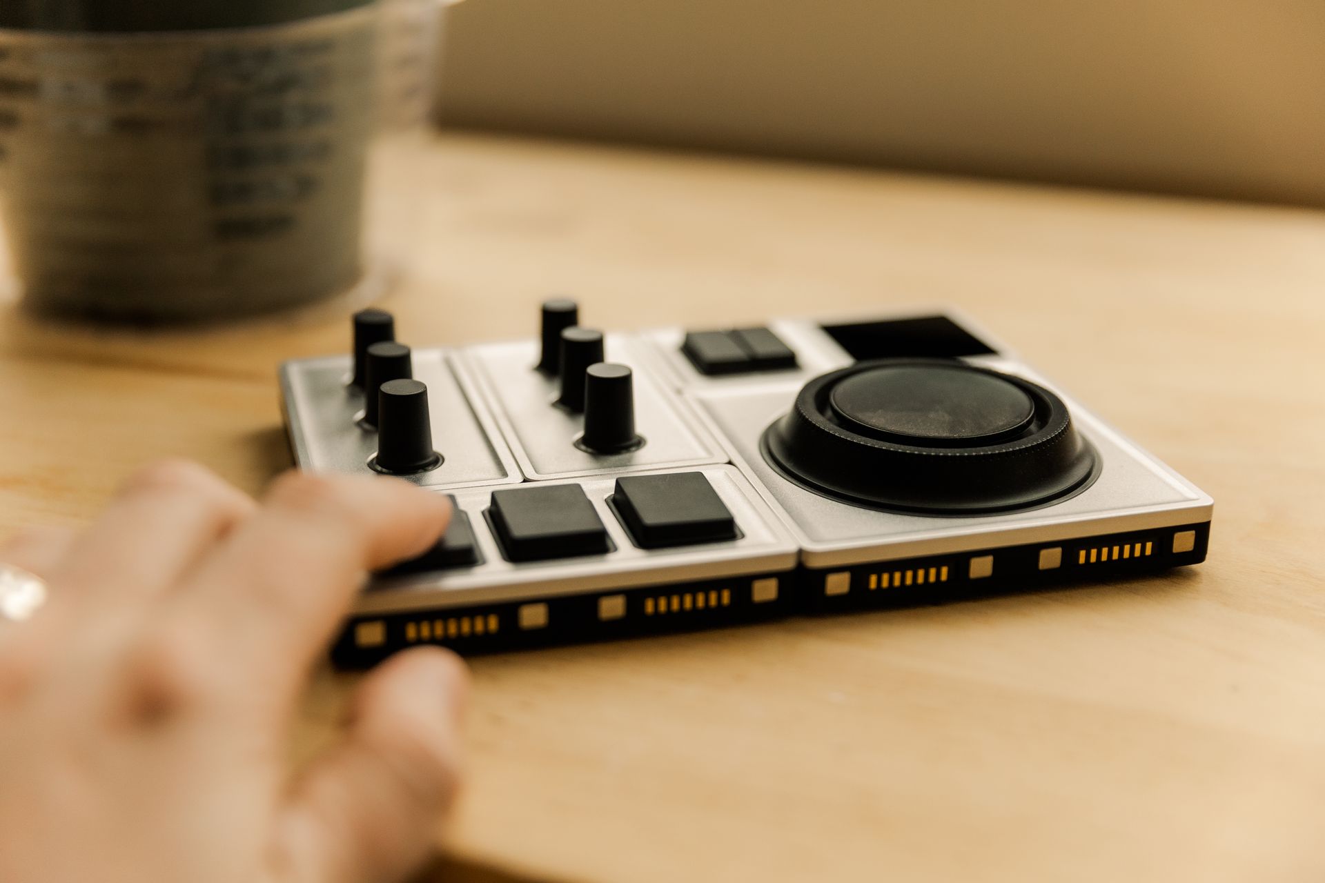 A person is using a mixer on a wooden table.
