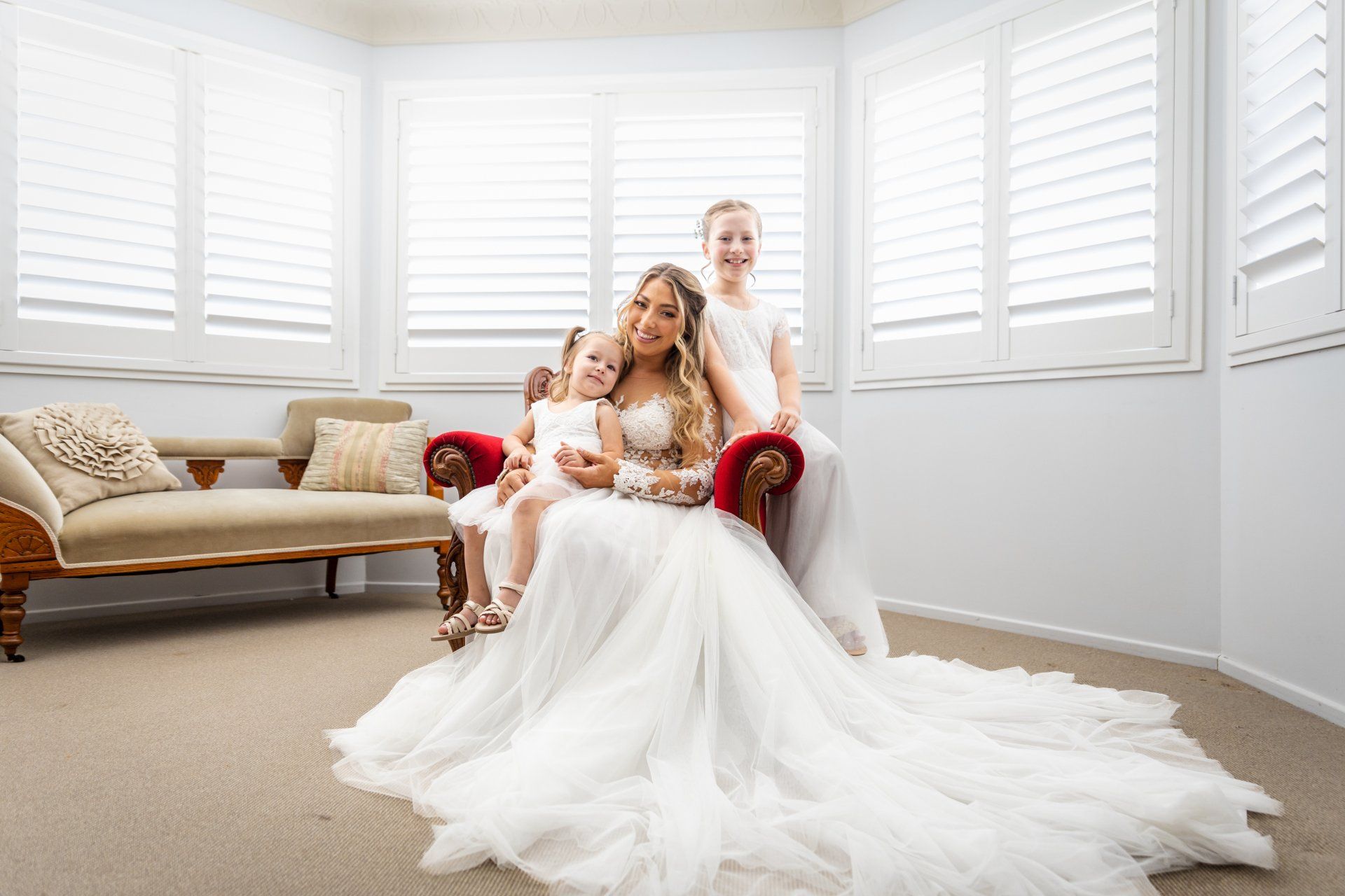 Wedding Video - a bride in a wedding dress is sitting on a couch with two flower girls .