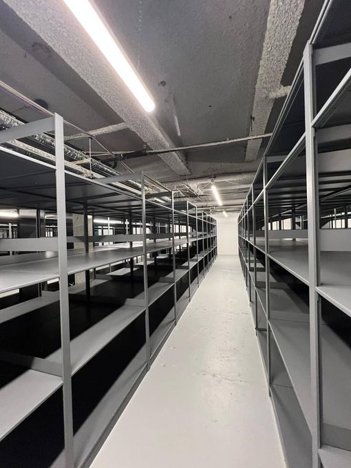 Empty industrial storage aisle with metal shelving and bright overhead lights